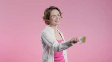 Pembe arka planda fırçası olan genç beyaz kadın sanatçı. Yaratıcı kişi, fantezi, fikir, hayata standart olmayan yaklaşım. Yüksek kalite 4k