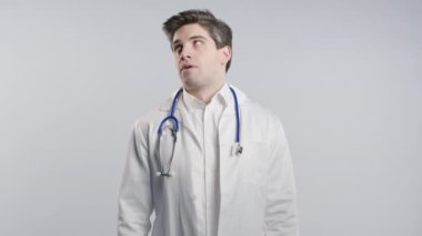 Sıkıcı doktor iç çeker ve gözlerini devirir. Kliniğin arka planında beyaz önlüklü. Doktor çalışmaktan yoruldu, hayal kırıklığına uğradı, çaresiz kaldı. Yüksek kalite 4k görüntü