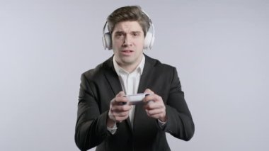 Yakışıklı esmer iş adamı beyaz stüdyo arka planında izole edilmiş joystick ile TV 'de heyecan verici video oyunu oynuyor. Modern teknolojiyi kullanarak. 4k