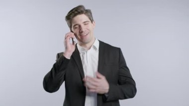 Olgun gülümseyen, olgun Amerikan Yöneticisi CEO patron telefonla konuşuyor, hoş bir şaka, gülümsüyor. Beyaz arka planda genç bir adam. Akıllı telefon görüşmesi. Yüksek kalite 4k