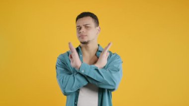 Ciddi şekilde hoşnutsuz, hiçbir işaret olmadan onaylamayan, reddeden, onaylanmayacak şekilde başını sallayan bir adam. Reddetmek, reddetmek, anlaşmazlık, sarıda genç adamın portresi, olumsuz cevap. Yüksek kalite 4k