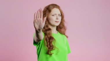 Avuç içi işaretini onaylamayan, stil düşkünü genç bir kadın. Benimle oynama, bu kadar yeter. Pembe arka planda bayan portresi. Yüksek kalite 4k