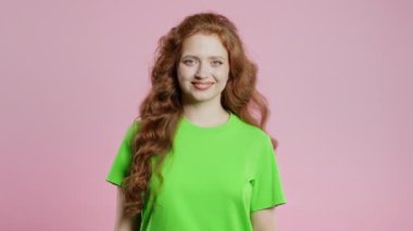 Kırmızı, uzun kıvırcık saçlı, yeşil tişörtlü, doğal güzellikte bir kadın. Pembe gözlü genç kız. Amerikan beyazları kameraya bakıyor. Yüksek kalite 4k