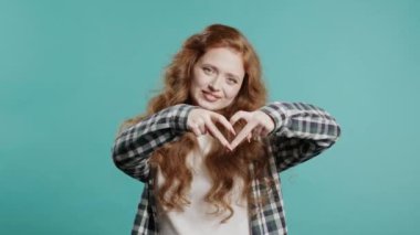 Gülümseyen kadın kalbinin şeklini gösteriyor. Mavi 'de pozitif kadın var. Sevgi. Kadın sağlığı, gönüllülük, bağış, minnettarlık sembolü, flört konsepti. Yüksek kalite 4k