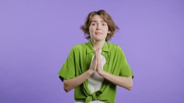 Genç bir kadın dua ediyor, özür diliyor, o suçlu. Menekşe arkaplan. Umut dolu dua eden kız, birinden arzularını tatmin etmesini ister, yardım ister. Yüksek kalite 4k