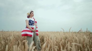 Hamile Vatansever Kadın Kırsal Buğday Tarlası 'nda Amerikan Bayrağıyla Duruyor. Demokrasi, bağımsızlık, ABD, 4 Temmuz kutlamaları, ABD bayrağı, seçim, Amerika, işgücü