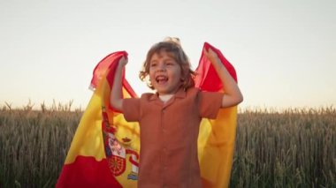 İspanyol taraftar çocuk kutlama yapıyor. Açık alanda ulusal Espana bayrağıyla atlıyor. İspanya ülkesi, futbol taraftarı, şampiyonluk konsepti.