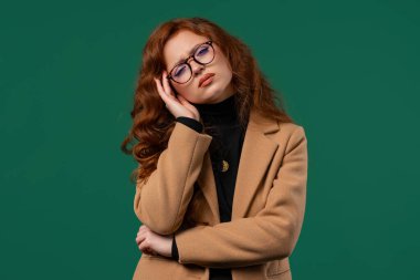 Acı çeken güzel bir kadının portresi baş ağrısı, yeşil stüdyo portresi. Kadın ellerini başının üstüne koyuyor. Migren sorunları, ilaç, hipertansiyon, manyetik fırtınalar kavramı.