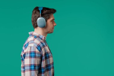 Müzik dinleyen yakışıklı bir adam. Mavi stüdyo arka planında modern kulaklıklarla dansın tadını çıkarıyor. Radyo, kablosuz modern ses teknolojisi, çevrimiçi çalar. Yüksek kalite
