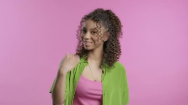 Güzel, genç, Afrikalı bir kadın ona katılmasını istiyor. El sıkışma jesti ile işaret ediyor. Güzel bayan arıyor - Hey sen, buraya gel. Oyuncu, davetkar. Pembe stüdyo arka planı