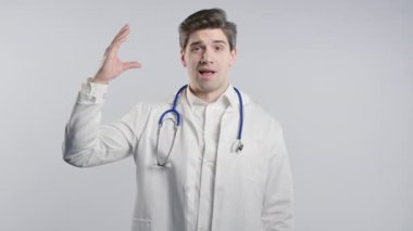 Sıhhiye ceketli yakışıklı doktor elleri ve beyaz arka planda izole edilmiş yuvarlanan gözleriyle jest yapıyor. Boş vaatler, falan filan. Yalancı! Yüksek kalite 4k görüntü