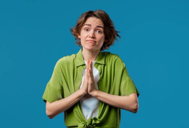 Genç bir kadın dua ediyor, özür diliyor, o suçlu. mavi arka plan. Umut dolu dua eden kız, birinden arzularını tatmin etmesini ister, yardım ister. Yüksek kalite