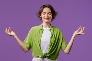 Sakin kadın rahatlıyor, meditasyon yapıyor, stresi reddediyor. Kadın derin nefes alıyor, Violet stüdyosunun arka planını sakinleştiriyor. Yoga, ahlaki denge, zen konsepti. Yüksek kalite