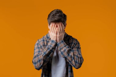 Şaşkın adam panik içinde çaresizlik jesti yapıyor, hayır, unuttum. Üzüntü, pişmanlık, drama, başarısızlık, sarı arka planda sorunlar hisseden bir adam. Yüksek kalite