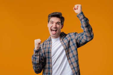 Olgun bir adam zaferi gösterir. Zaferin jesti, başarıya, amaca ulaşmıştır. Mutlu, mutlu, şaşırmış, sarı arka plandaki mutlu adam. Büyük ikramiye konsepti. Yüksek kalite