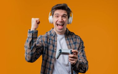 TV 'de heyecan verici video oyunu oynayan yakışıklı genç adam sarı stüdyo arka planda izole edilmiş joystick ile. Modern teknolojiyi kullanarak.