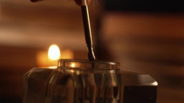 Tüylü kalemle mektup yazan adam, yanan eski mumların sıcak ışığı altında. Beyefendi mürekkebe elini daldırır. 18. ya da 19. yüzyıldan özel bir sahne. Yazışma konsepti. kalite 4k