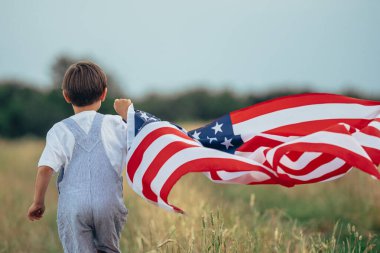 Sevimli çocuk - Amerikan vatansever çocuk kırsal yolda bayrak sallayarak koşuyor. ABD, 4 Temmuz - Bağımsızlık Günü, Kutlama. ABD bayrağı, Gaziler Anıtı, Seçim, Amerika, İşçi Partisi