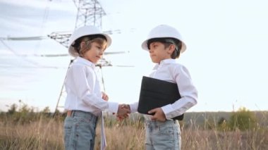 Küçük çocuklar el sıkışıyor. Tokalaşma, takıma hoş geldin, tanıtım ya da işe alım. Elektrik endüstrisi işi, elektrik direği geçmişinde çok zeki çocuklar. Yeşil enerji sürdürülebilirliği, yenilenebilir