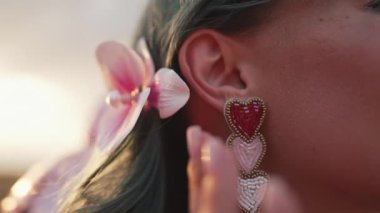 Romantik Boncuklu Kalpler Mücevher Küpeleri ve orkide tokası takan genç bir kadın. Mücevher Detayları. Romantik kıyafet, parti. Yüksek kalite 4k görüntü