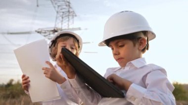 Mühendis olarak oynayan küçük çocuklar veya güvenlik kasklarıyla tablet kullanan yöneticiler. Elektrik endüstrisi mesleği, aktarım elektrik hattında çalışan çok zeki çocuklar. Yüksek kalite 4k görüntü