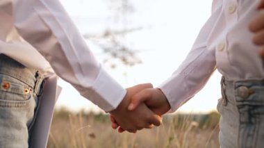 Güvenlik kasklı mühendislik oynayan çocuklar, iş arkadaşları el sıkışıyor. İşbirliği, sözleşme. Elektrik endüstrisi işi, şanzıman hatlarında çalışan zeki çocuklar. 4K.