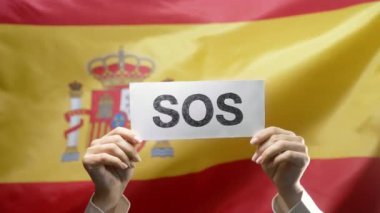 SOS, alarm, Espana bayrak geçmişinde acil durum kartı olan kadın eller. İşçi sömürüsü, göçmenler, mülteciler, insan kaynakları, yardım talebi, çevre bakımı. Yüksek kalite 4k görüntü