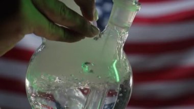 Tıbbi marihuana içen bir kadın, Amerikan bayraklarında cam su nargilesi. Esrar tütünü, Amerika 'da Shisha, Birleşik Devletler. Yüksek kalite 4k görüntü