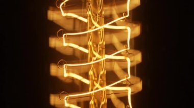 Karanlık bir gecede parıldayan Edison Tungsten lambası, siyah arka plan, sıcak sarı ışık, retro ampul, antika form. Yaratıcı fikir, farkındalık, keşif, eureka. Nabız. Yüksek kalite 4k