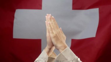 İsviçre bayrağının arka planında beyaz haçta dua eden bir kadın. Umut dolu bir dua. Meditasyon, okuma, düşünceleri, istekleri ya da minnettarlığı İsviçre 'ye iletir. Yüksek kalite 4k görüntü