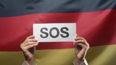 SOS, alarm, Deutschland bayrağı geçmişinde acil durum kartı olan kadın eller. İşçi sömürüsü, göçmenler, mülteciler, insan kaynakları, yardım talebi, çevre bakımı. Yüksek kalite 4k görüntü