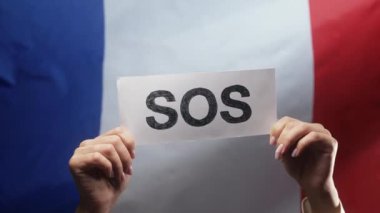 SOS, alarm ve acil durum kartı olan Fransız bayrağı geçmişi olan bir kadın. Fransa işçi sömürüsü, göçmenler, mülteciler, insan kaynakları, yardım talebi, çevre bakımı. Yüksek kalite 4k