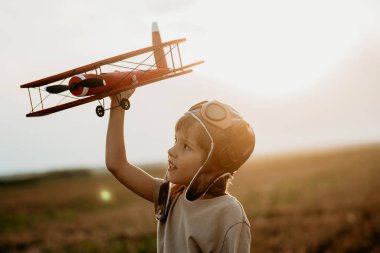 Çocuk, tahta vintage uçakla koşuyor. Pilot olmayı hayal eden bir çocuk. Hayal gücü özgürlüğü, her yerde seyahat, aktif çocukluk. Yüksek kalite fotoğraf