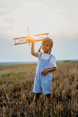 Çocuk, tahta vintage uçakla koşuyor. Pilot olmayı hayal eden bir çocuk. Hayal gücü özgürlüğü, her yerde seyahat, aktif çocukluk. Yüksek kalite fotoğraf