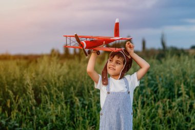 Gülümseyen 5 yaşındaki anaokulu çocuğu tahta eski model uçak oyuncaklarıyla oynuyor, gelecekteki mesleki ilgilerini keşfediyor, hayalperest çocuk uçuyor, seyahat ediyor..