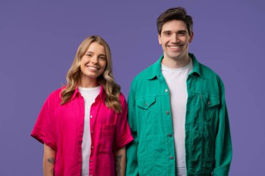 Violet stüdyosunun arka planında genç yetişkin portresi olan güzel bir kadın. Arkadaş canlısı çift gülümsüyor. Renkli canlı bir kıyafet. Yüksek kalite