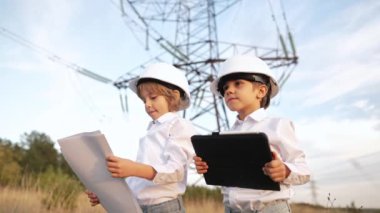 Mühendis olarak oynayan küçük çocuklar veya güvenlik kasklarıyla tablet kullanan yöneticiler. Elektrik endüstrisi mesleği, aktarım elektrik hattında çalışan çok zeki çocuklar. Yüksek kalite 4k görüntü