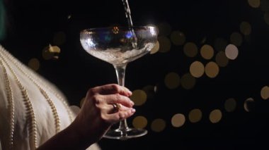Tatil kıyafetli tanınmayan bir kadın düğünü kutluyor. Şampanya içmek ya da Retro Style Glass 'dan şarap içmek. Yaz bahçesinde ışıklı bir parti. Uzayı kopyala Yüksek kalite 4k görüntü