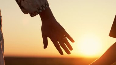 Anne ve çocuk gün batımında el ele tutuşuyorlar. Oğul ya da kız olarak siluet anne elini tutuyor. Güneş patlamaları. Aile, güven, aşk ve mutluluk kavramı. Yüksek kalite 4k görüntü