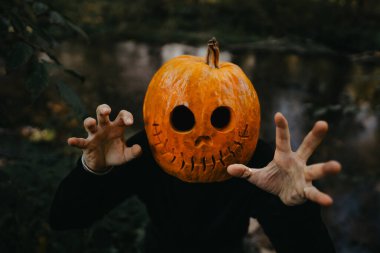 Cadılar Bayramı için balkabağı kafalı korkunç bir adam. Balkabağı kostümü. Şeker mi şaka mı? Çerçevenin ortasına portakal kabağı. Yüksek kalite fotoğraf