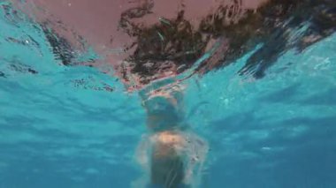 Mutlu küçük çocuk havuza atlıyor açık mavi su, çocuklar için eğlence. Yaz yüzüşü, sualtı eğlencesi. Komik çocuk, dalmanın tadını çıkar. Aşırı açı. Yüksek kalite 4k görüntü