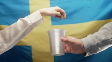 Zengin kadın Krona 'yı İsveç bayrağında sadaka isteyen evsiz bir adamın plastik bardağına fırlatıyor. Paylaşmak ve birbirimize yardım etmek. Yoksul hayat, işsizlik, yoksulluk sınırının altındaki insanlar. 4k görüntü