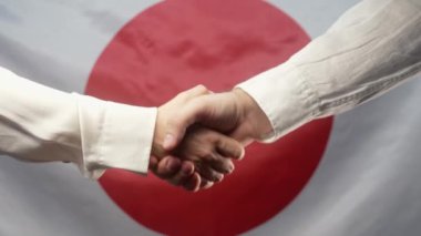 Japon erkek ve kadın iş ortakları el sıkışıyor. Tokalaşma, bir anlaşma yap, takıma hoş geldin, Japonya bayrağını tanıtma ya da işe alma. Uluslararası işbirliği, sözleşme konsepti. 4k