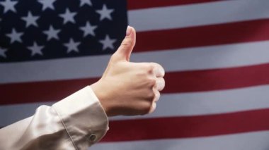 Kadın, Amerikan bayrağı arkaplanında el işareti yapıyor. Doğru mükemmel seçim, harika anlaşma. Pozitif, onay, güven konsepti. Yüksek kalite 4k görüntü