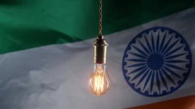 Hint bayrağı arka planında parlayan Edison ampulü. Elektrik fiyatları, faturalar, enerji krizi, vergi artışı. Yüksek kalite 4k