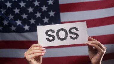 Kadın eli Sos, Alarm, Amerikan Bayrak Arkaplanda Acil Durum Kartı. ABD, işgücü sömürüsü, göçmenler, mülteciler, insan kaynakları, yardım talebi, çevre bakımı. Yüksek kalite 4k görüntü