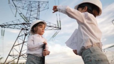 Güvenlik kasklı mühendisler ya da yöneticiler gibi davranan küçük çocuklar şantiyede çalışmaktan bahsediyorlar. Elektrik endüstrisi mesleği, aktarım elektrik hattında çalışan çok zeki çocuklar. kalite 4k