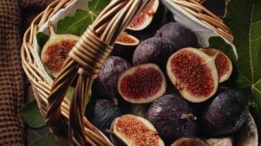 Taze incir hasadı hasat sepetinde, yapraklarla, kırsal ahşap masa servisleriyle. Ficus carica. Güzel mevsimlik meyveler, vejetaryen yemekleri. Üst Manzara. Dolly kaydırma atışı. Yüksek kalite 4k görüntü 