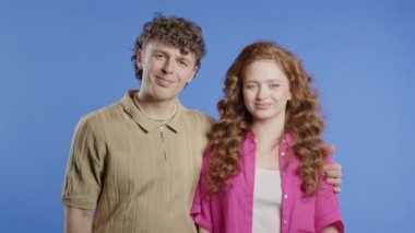 Violet stüdyosunun arka planında genç yetişkin portresi olan güzel bir kadın. Arkadaş canlısı çift gülümsüyor. Renkli canlı bir kıyafet. Yüksek kalite 4k