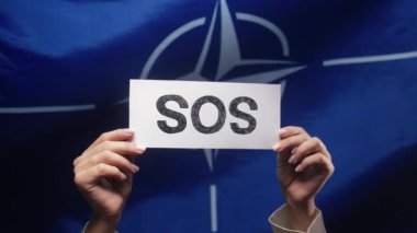 Kadın eli Sos, Alarm, NATO OTAN Bayrak Arkaplanda Acil Durum Kartı. Yardım talep ediyorum, çevresel bakım. Yüksek kalite 4k görüntü